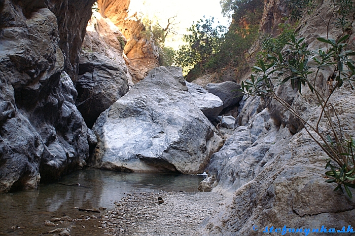 Moja konečná v Sarakina gorge na Kréte. Posledný kameň vpravo. Úzke miesto, kde končili vysekané stupy a bolo potrebné prejsť rozporom po šmykľavej skale ponad úzku, dosť hlbokú vodu. V skale napravo bola osadená jedna skrutka, z ktorej visel tenký konopný špagátik. Nič nebezpečné, ibaže ak by som sa šmykol, ocitol by som sa celý vo vode. Keďže som techniku nemal komu prenechať, rozhodol som sa pre otočku