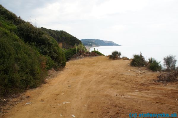 Koniec poľnej cesty s vyhliadkou na Santa Barbaru. Cesta pokračuje na pláž úvozom (mierne vľavo a potom dosť prudko doprava). Končí na veľkých okruhliakoch pri mori. Po približne 200 metroch kamene končia a začína piesok