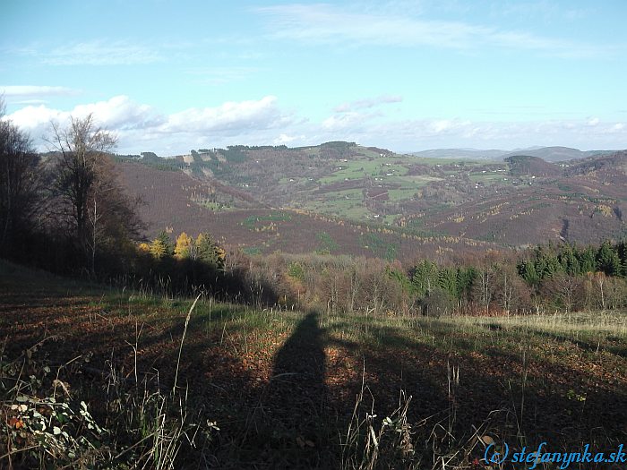 Zostup z Veľkého Lopeníka do Novej Bošáce. Zľava (za stromom) Mikulčin vrch, v strede Tomkúv vrch (za ním je chata Vyškovec), dolu do sedla k pamätníku letcom pri kopčeku Hřibovna a začínajúci kopček úplne vpravo je Kykula