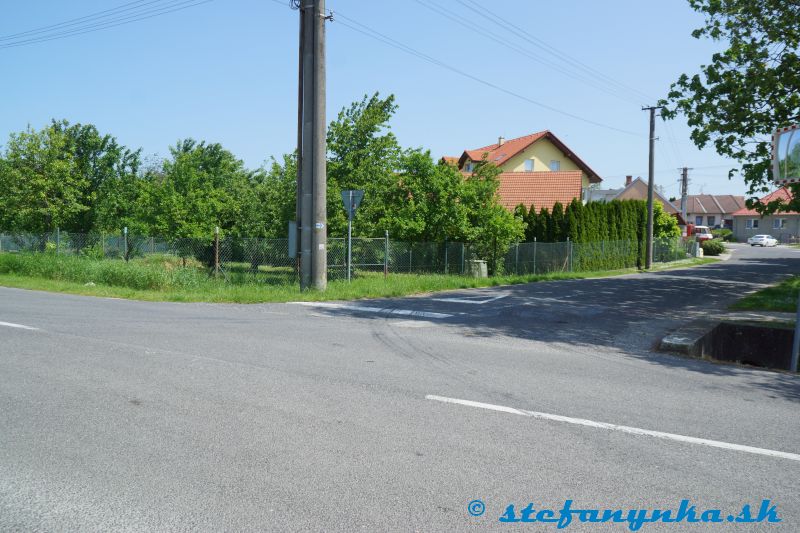 Rybky. Cesta od Senice (vpravo mimo obraz) po Kríž (vľavo mimo obraz). Pôvodná značka prichádza od toho bieleho auta na križovatku a zahýba doprava. Nová prichádza na križovatku odo mňa.Tá modrá šípka na stĺpe je evidentne nezmysel aj pre starý aj nový variant.