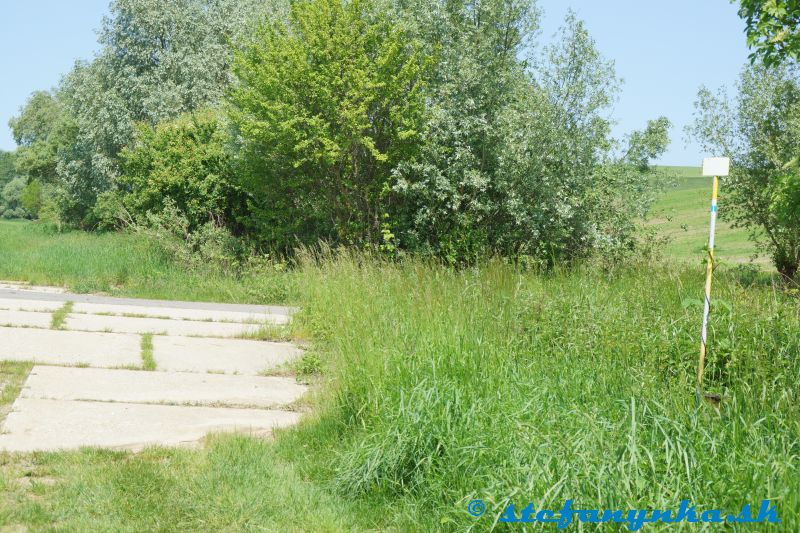 Rybky / Rohov. Betónová cesta. Doľava viedlo pokračovanie k studničke. Smerom doprava viedla cesta do obce Rohov. Pár metrov za stromami sa nachádzal aj rázcestník Rohov